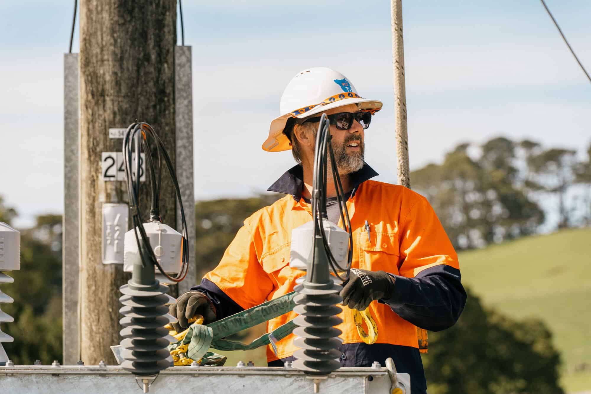 PLT lineman in orange hi-vis at a transformer