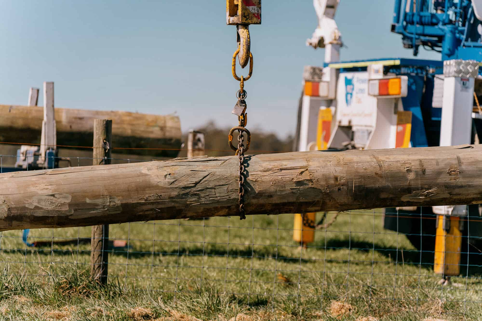 New power pole hanging from a crane hook ready for installation
